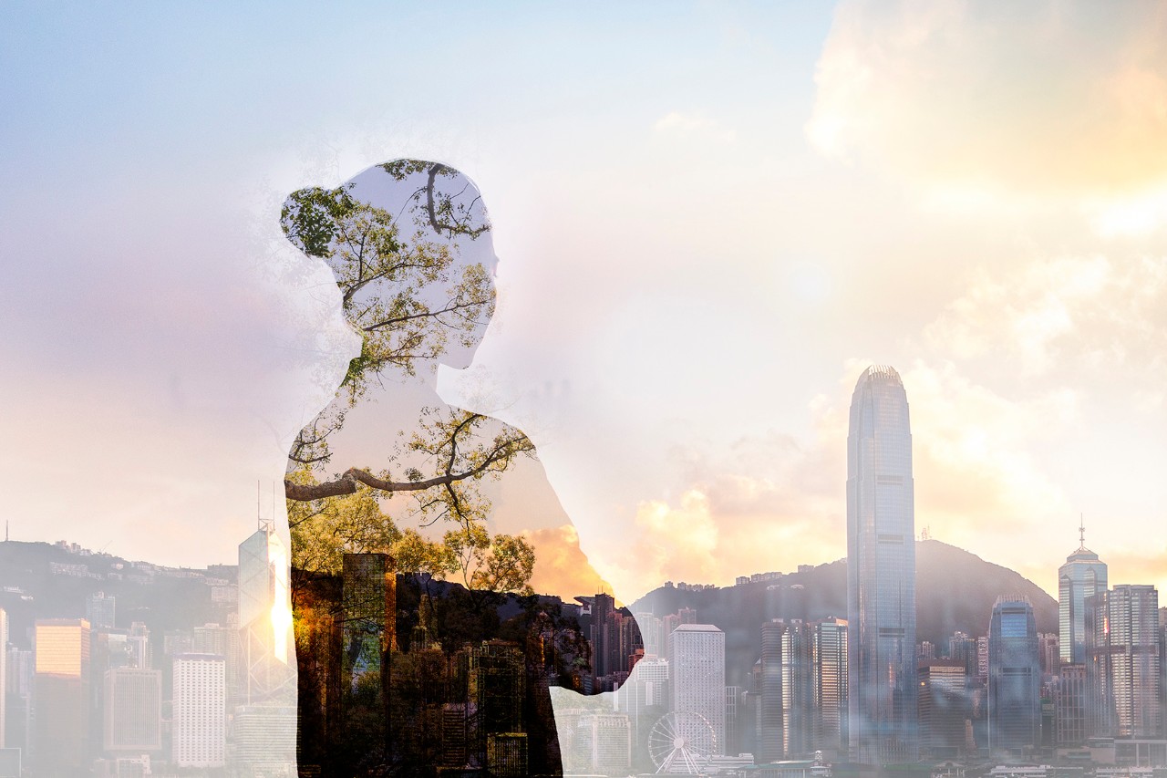 Person standing in contemplation in urban Hong Kong city reflection with nature trees