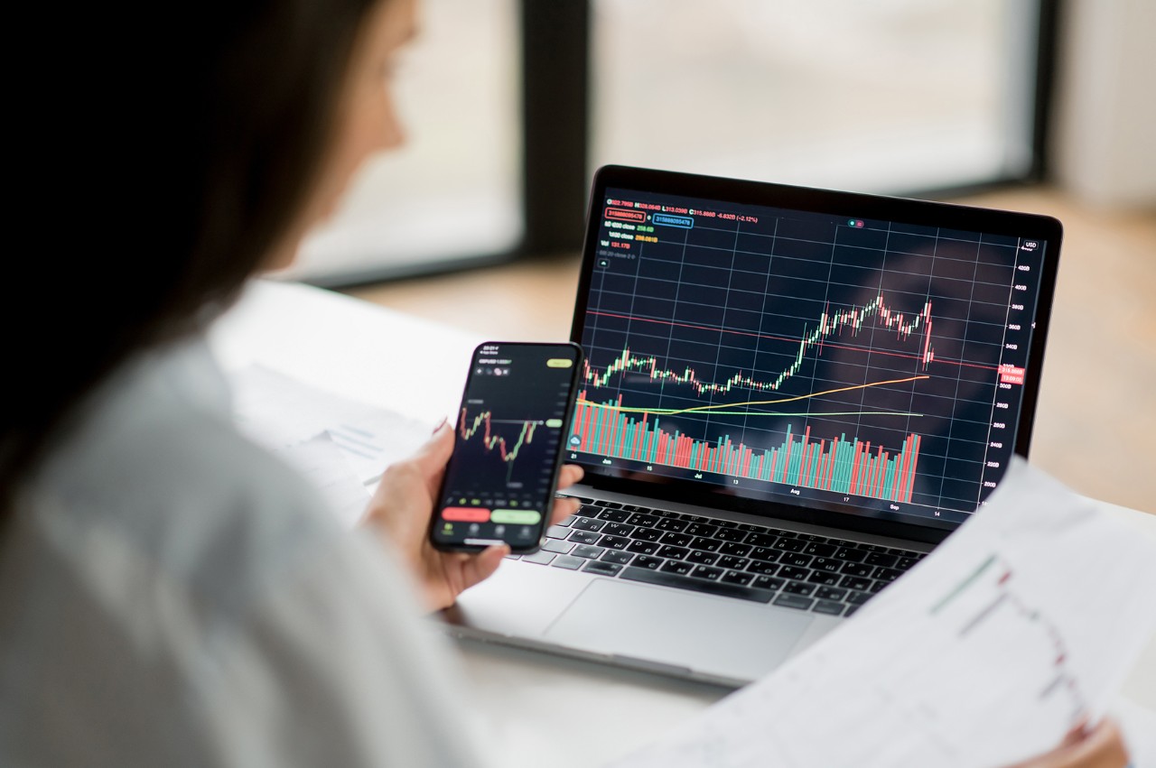 Woman investor and crypto trader, using laptop and smartphone