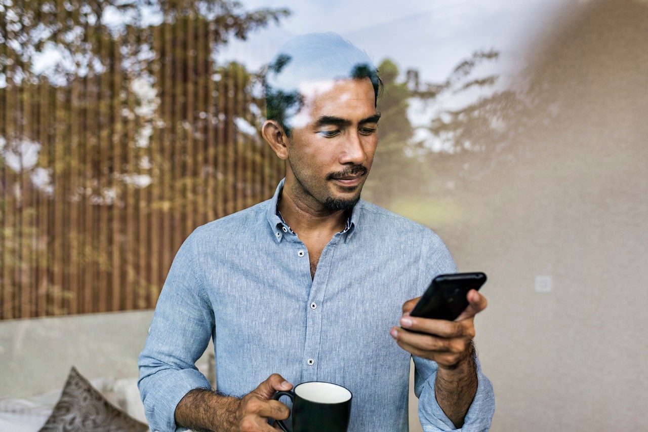 Man on his phone while drinking his coffee