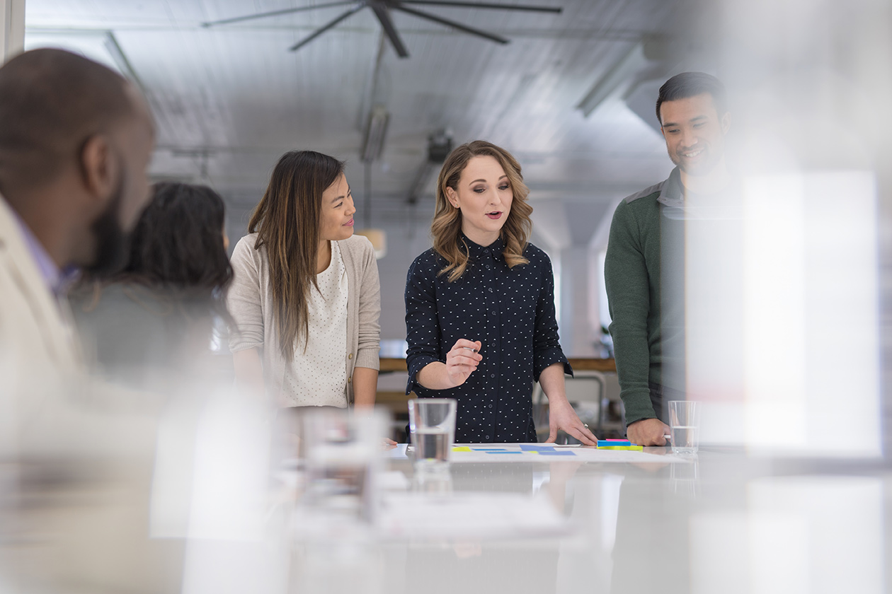 Team meeting, woman speaking and showing a plan on paper